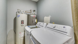A laundry area with a wall-mounted washer and dryer, a vent, and a safety sign.