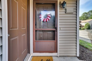 A brown front door with a glass panel, a doormat, and a wall-mounted light fixture. - Bristol Condo Near ESPN HQ & Lake Compounce! (Bristol)