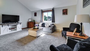 Ein Wohnzimmer mit Fernseher, Sofa, Couchtisch und Lampe.