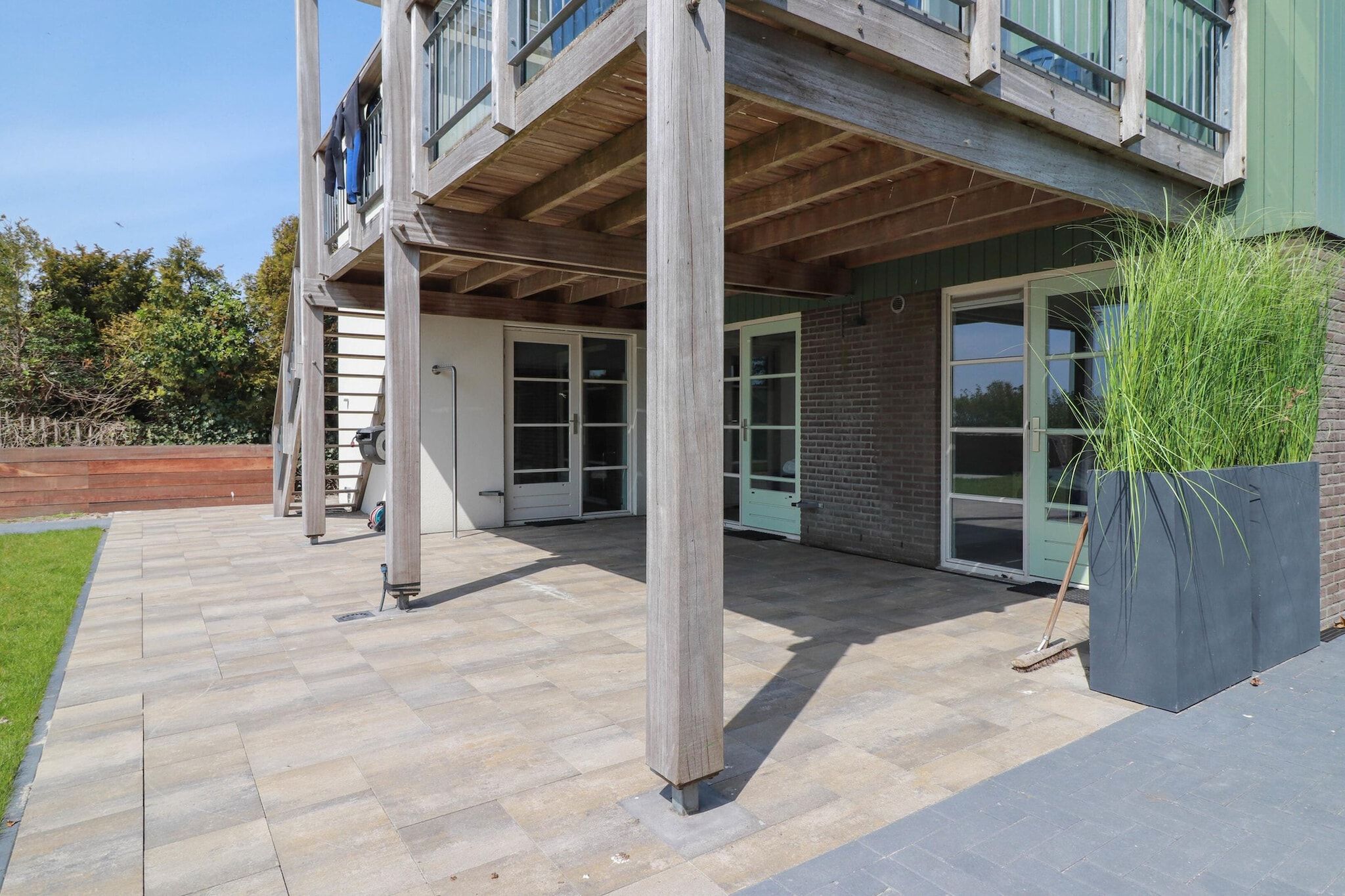 Um edifício moderno com deck de madeira, grandes portas de vidro e fachada de tijolos.