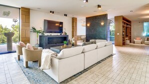 A spacious living room with a large sofa, a coffee table, and a flat-screen TV mounted on the wall. - 6,000-Sq-Ft Hollywood Hills Home w/ Pool, Hot Tub (Los Angeles)