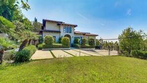 A two-story house with a tiled roof, a central archway, and a well-maintained lawn. - 6,000-Sq-Ft Hollywood Hills Home w/ Pool, Hot Tub (Los Angeles)