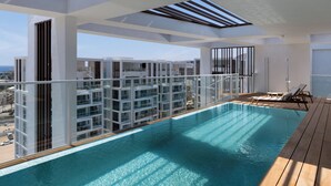 Un edificio residencial moderno con piscina en la azotea, ventanas amplias y vistas de la ciudad.