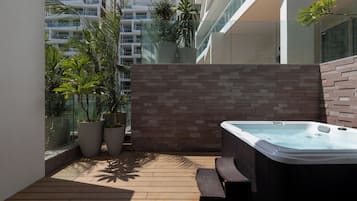 Un espacio exterior moderno con jacuzzi, plantas en macetas y una pared de ladrillo.