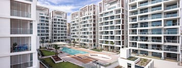 Un edificio residencial moderno de varios pisos con piscina en la azotea.