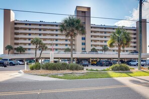 A multi-story hotel with a parking garage and several palm trees in the foreground. - Unwind Poolside, Walk to Shore! Ponce Inlet Escape (Ponce Inlet)