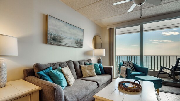 A modern living room with a sofa, a coffee table, a lamp, a painting, and a balcony with a view. - Unwind Poolside, Walk to Shore! Ponce Inlet Escape (Ponce Inlet)