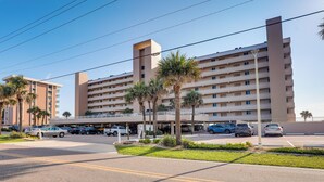 A multi-story hotel with a parking lot in front, featuring palm trees and a clear sky. - Unwind Poolside, Walk to Shore! Ponce Inlet Escape (Ponce Inlet)