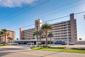 A multi-story hotel with a parking lot in front, featuring palm trees and a clear sky. - Unwind Poolside, Walk to Shore! Ponce Inlet Escape (Ponce Inlet)