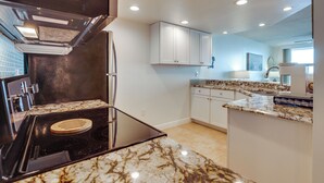 A modern kitchen with a built-in stove, white cabinets, and a marble countertop. - Unwind Poolside, Walk to Shore! Ponce Inlet Escape (Ponce Inlet)