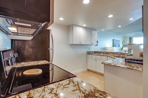 A modern kitchen with a built-in stove, white cabinets, and a marble countertop. - Unwind Poolside, Walk to Shore! Ponce Inlet Escape (Ponce Inlet)