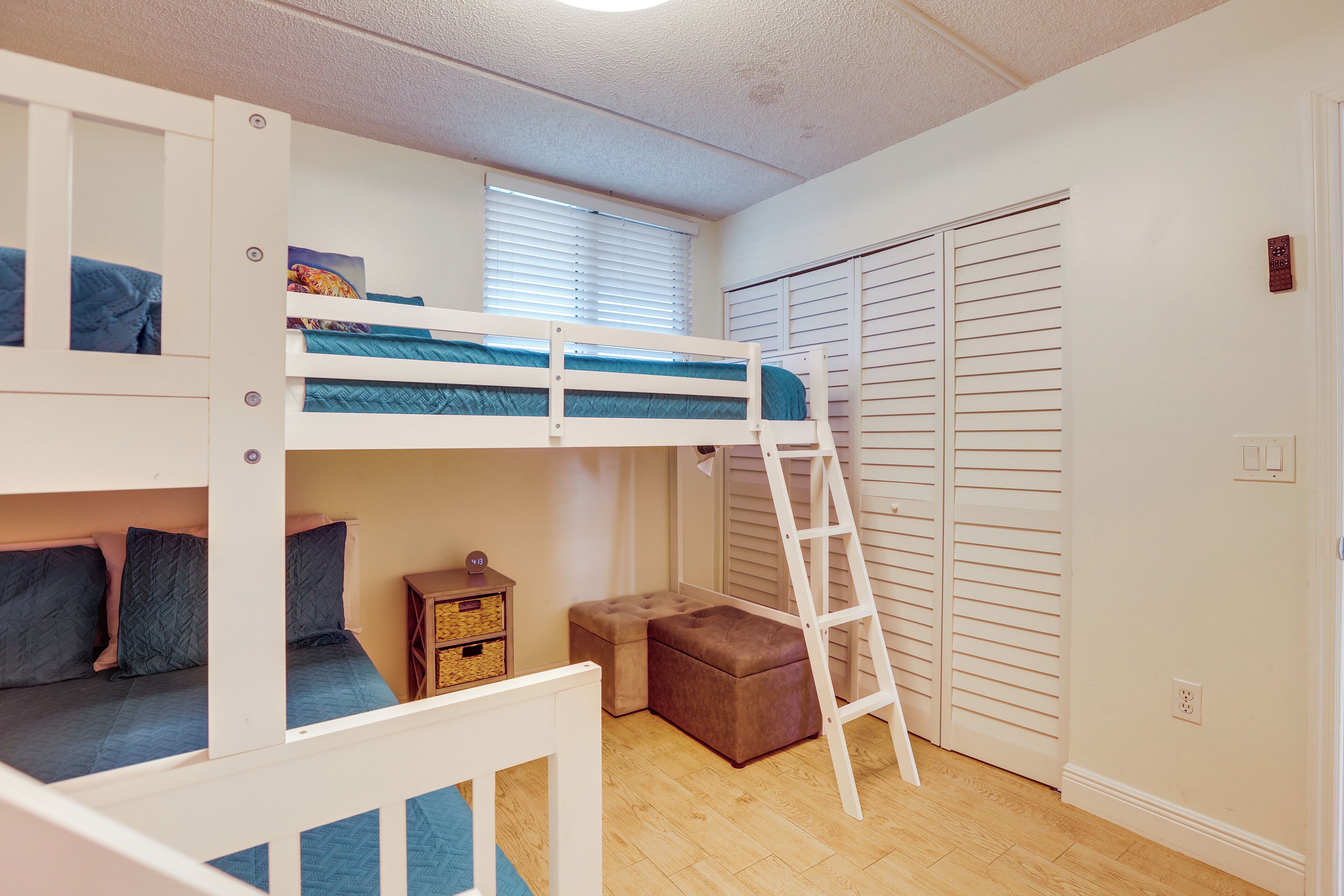 Ein Schlafraum mit Etagenbett, einer kleinen Kommode und einem Kleiderschrank mit Schiebetüren.