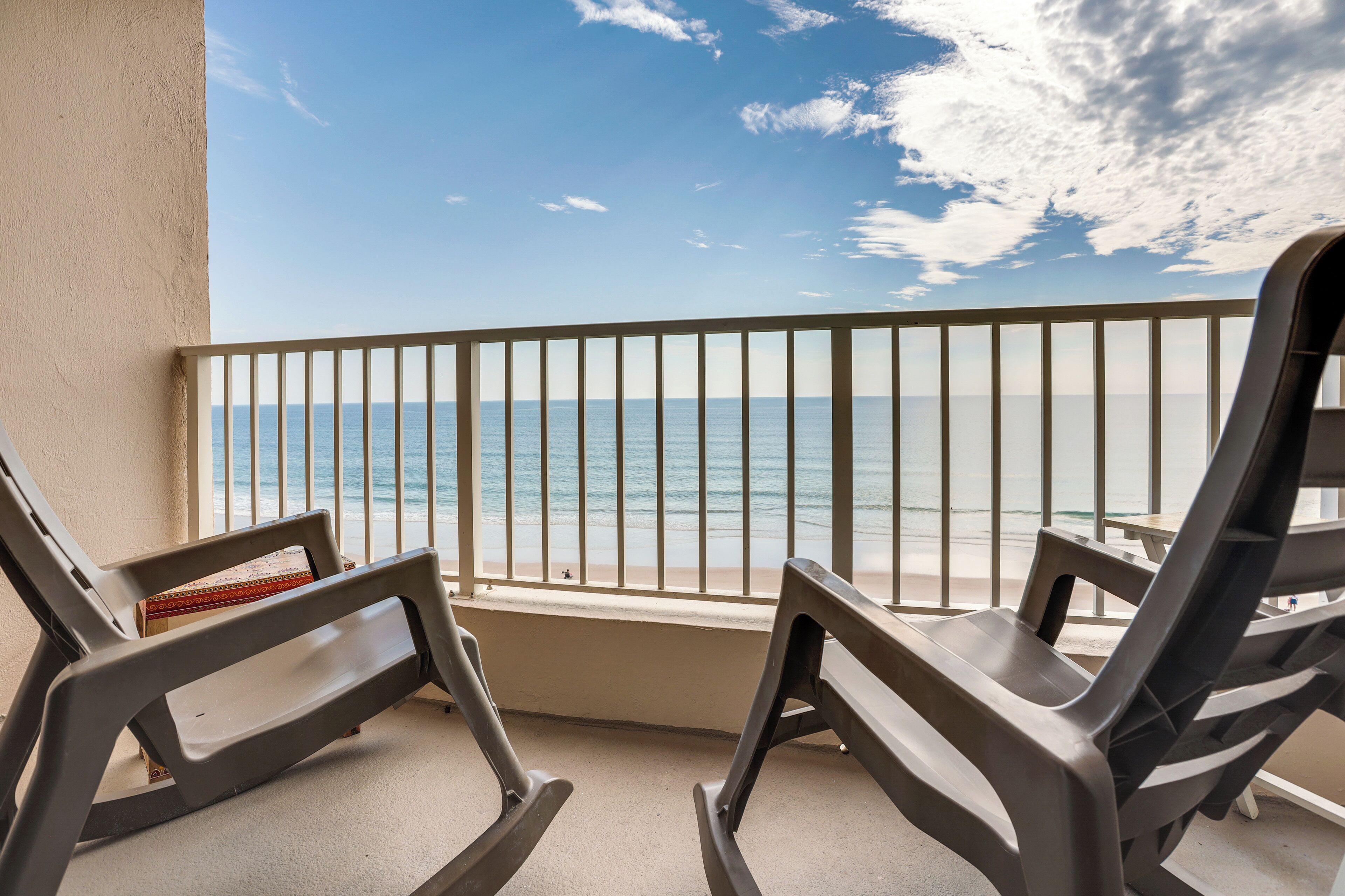 Ein Balkon mit zwei Stühlen und Blick aufs Meer, inklusive Geländer.