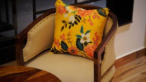 A wooden chair with a floral cushion. - Ranthambore Bunglow (Sawai Madhopur)