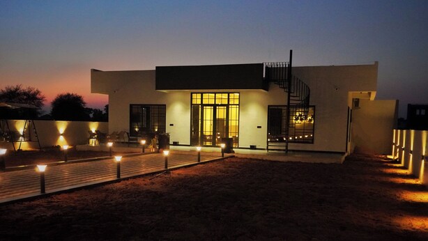 A modern house with a flat roof, a central staircase, and a well-lit entrance. - Ranthambore Bunglow (Sawai Madhopur)
