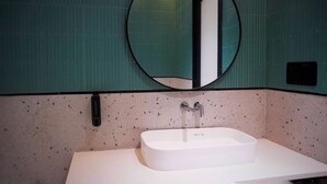 A bathroom with a white sink, a round mirror, and a green tiled wall. - Ranthambore Bunglow (Sawai Madhopur)
