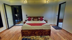A modern bedroom with a large bed, wooden headboard, and a patterned rug. - Ranthambore Bunglow (Sawai Madhopur)