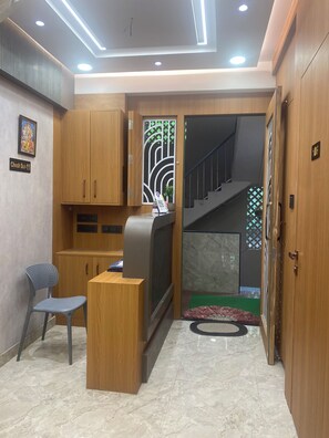 Un vestíbulo de hotel con mostrador de recepción, zona de estar, escalera y un muro decorativo.