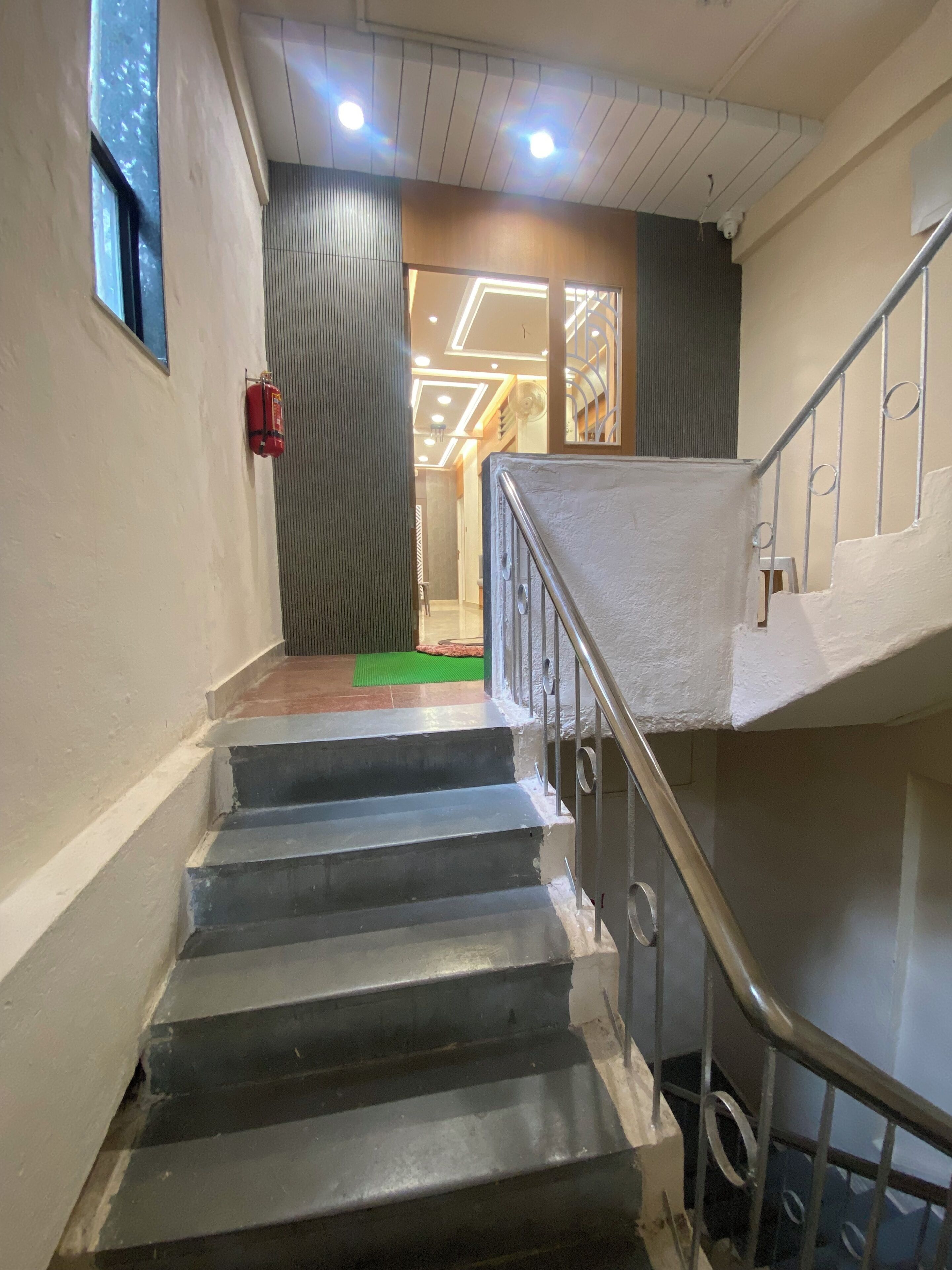 A staircase with metal railings, a fire extinguisher on the wall, and a ceiling with recessed lighting.