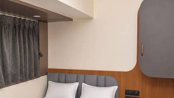 Una habitación de hotel con una cama, un ventilador de techo, un armario y una mesita de noche con un teléfono.
