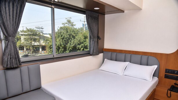 A bed with a headboard, a window with curtains, and a bedside telephone.