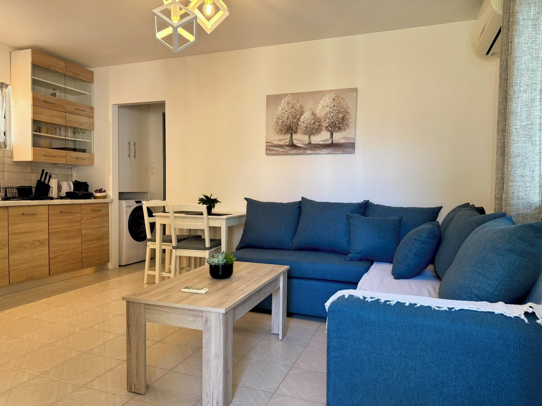 A modern living room with a blue sofa, a wooden coffee table, and a dining area with a white table and chairs.