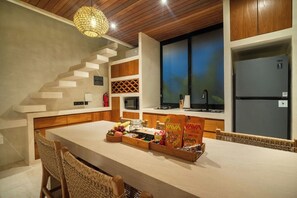 A modern kitchen with a central island, wooden cabinets, a built-in stove, and a refrigerator. - 1 BR Beachside Retreat Blacksand Villas Bingin (Badung)