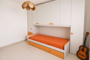 Een slaapkamer met een bed, een gitaar en een geweven lamp.
