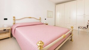 Een slaapkamer met een bed, nachtkastjes, een kledingkast en een stoel.