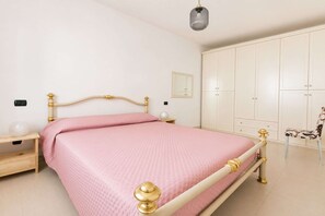 A bedroom with a bed, nightstands, a wardrobe, and a chair.