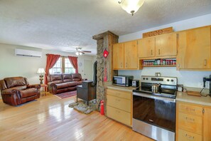 A living room with leather sofas, a fireplace, and a kitchen with wooden cabinets and stainless steel appliances. - Cozy Cabin Retreat: Peaceful Mountain Views (Dungannon)