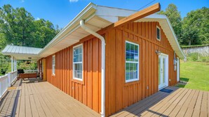 Ein Holzhaus mit überdachter Terrasse, großen Fenstern und einer Tür.