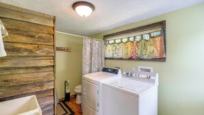 Ein kleines Badezimmer mit Holzvertäfelung, einer Waschmaschine und einer Toilette.