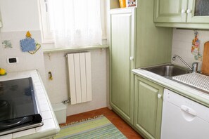 A compact kitchen with a stove, sink, and a small refrigerator. - Lakeside Apartment in Germignaga for 4 (Germignaga)