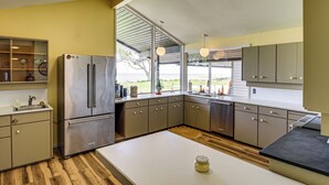 A modern kitchen with stainless steel appliances, wooden flooring, and large windows offering a view. - Bayfront Escape Near Boat Launch in Austwell (Austwell)