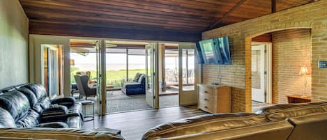 Un salón amplio con sofás de cuero, televisor y pared de ladrillo.