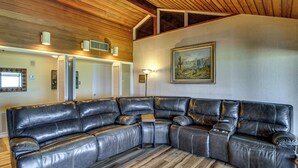 A sectional sofa in a room with wooden flooring, a ceiling with wooden beams, a wall-mounted painting, and a floor lamp. - Bayfront Escape Near Boat Launch in Austwell (Austwell)