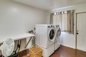 A laundry room with a washing machine, a drying rack, a fan, and a door. - Bayfront Escape Near Boat Launch in Austwell (Austwell)