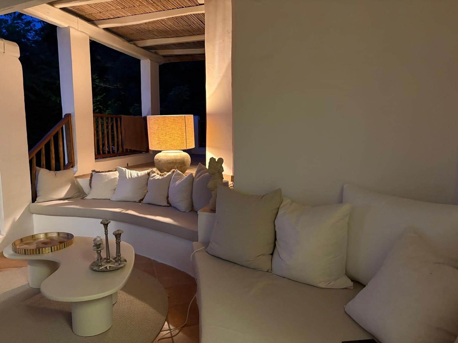 A cozy outdoor seating area with a sofa and a table, a lamp, and a decorative statue.