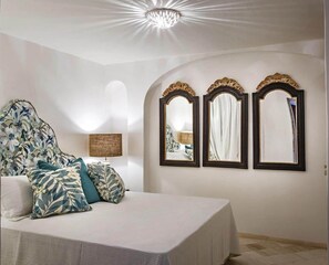 Ein Schlafzimmer mit einem Bett, einer Lampe und drei Wandspiegeln.