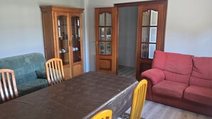 Een eethoek met een tafel, stoelen, een houten kast en een rode bank.