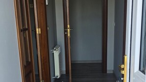 Een gang met houten deuren, een radiator en een witte deur met een sleutelhanger.