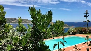 A pool with a view of the sea and hills in the background. - Punta Est - PERLA Two-Bedroom Apartment with Terrace and Ocean View (Capo Coda Cavallo)