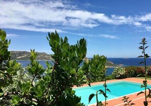 Ein Pool mit Blick auf das Meer und die dahinterliegenden Hügel.