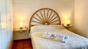 A room with a bed, two bedside lamps, a bedside table, and a wall-mounted shelf. - Punta Est - PERLA Two-Bedroom Apartment with Terrace and Ocean View (Capo Coda Cavallo)