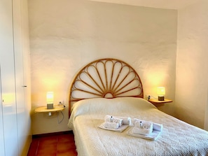 Ein Zimmer mit einem Bett, zwei Nachttischlampen, einem Nachttisch und einem Wandregal.