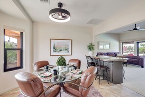 A modern dining area with a glass table, leather chairs, a central island with bar stools, and a ceiling fan. - 2 Mi to Lake Havasu! Mtn-View Poolside Paradise (Lake Havasu City)