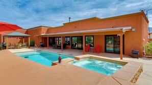 Un área de piscina con jacuzzi, mobiliario exterior y un patio cubierto.