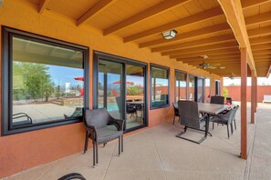 An outdoor patio with large windows, wicker furniture, and a ceiling fan. - 2 Mi to Lake Havasu! Mtn-View Poolside Paradise (Lake Havasu City)