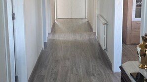 Ein Flur mit Holzboden, weißen Wänden und einer Deckenleuchte.